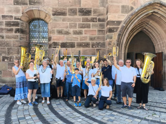 Die Bläserinnen und Bläser mit erhobenen Instrumenten vor der Jakobskirche in Nürnberg